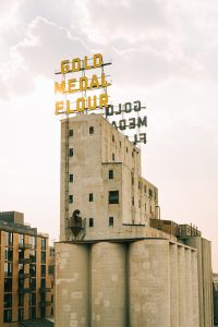 Historic gold medal flour building with silos and cityscape.