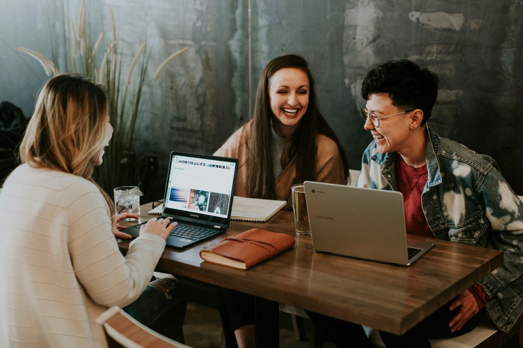 three people sitting in front of table laughing together three people sitting in front of table laughing together